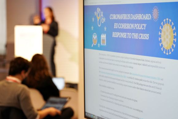 Could the pandemic be a chance to change how we view growth in Europe? Source: EURegions Week, Flickr A sign in the foreground showing information about covid and cohesion policy, speaker in the background